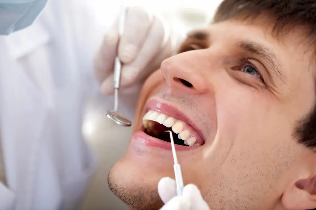 A person having their teeth examined with a mirror and probe