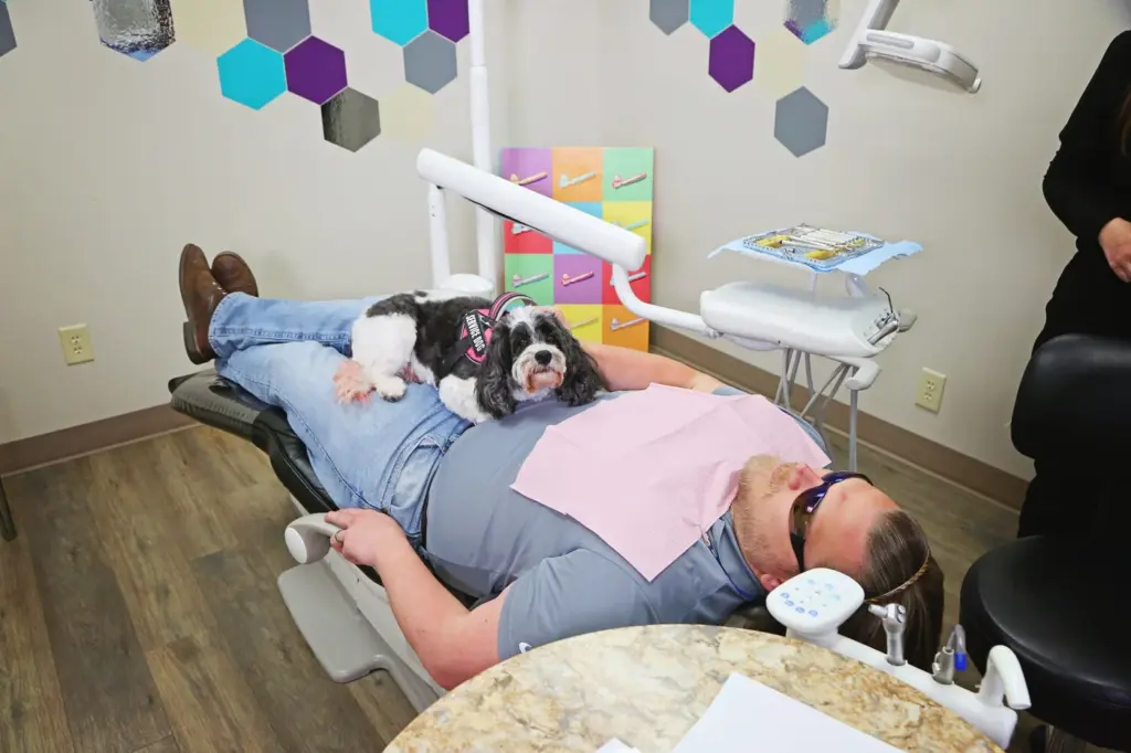 A therapy dog sitting on a patient during treatment at Diamond Dental in Tulsa